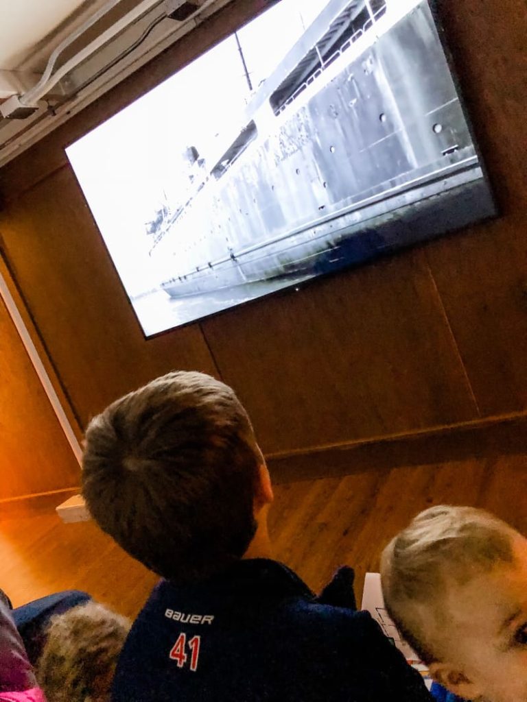 Boy and baby watching a black and white documentary about car ferry's.