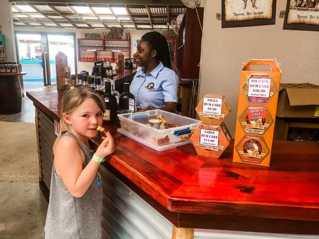 girl standing at a counter trying a sample of rum cake. 