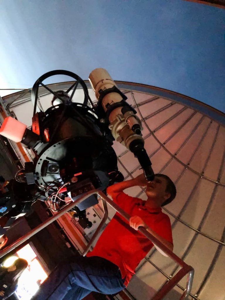 boy looking out of an observatory telescope. 