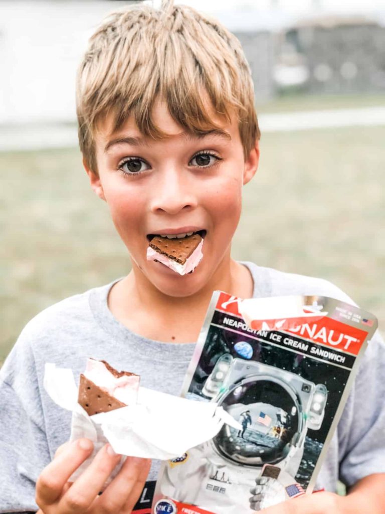 Boy wide eyed eating astronaut ice cream sandwich. 