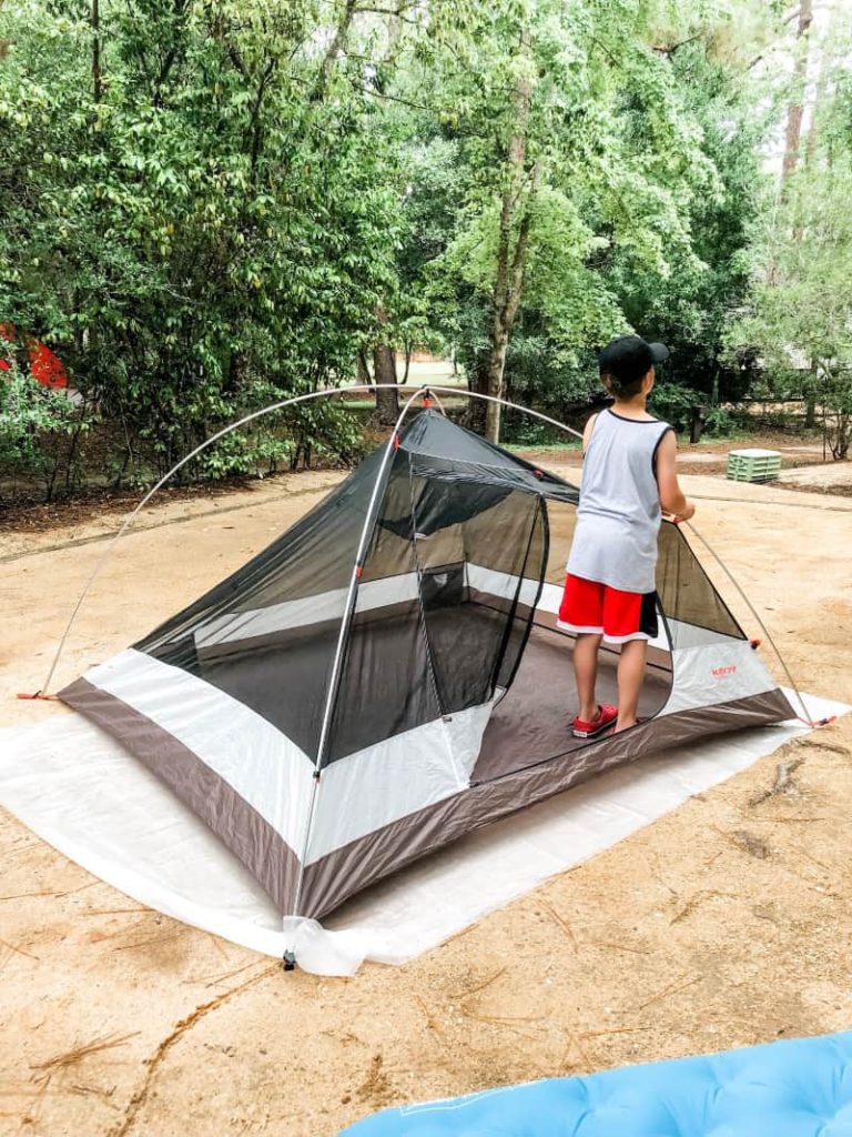 young boy setting up a tent on his own. 