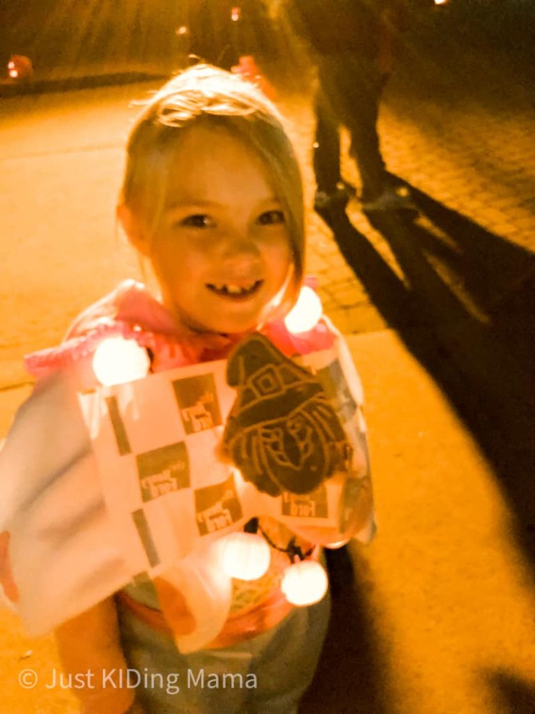 Girl holding a witch shaped cookie before she eats it. 