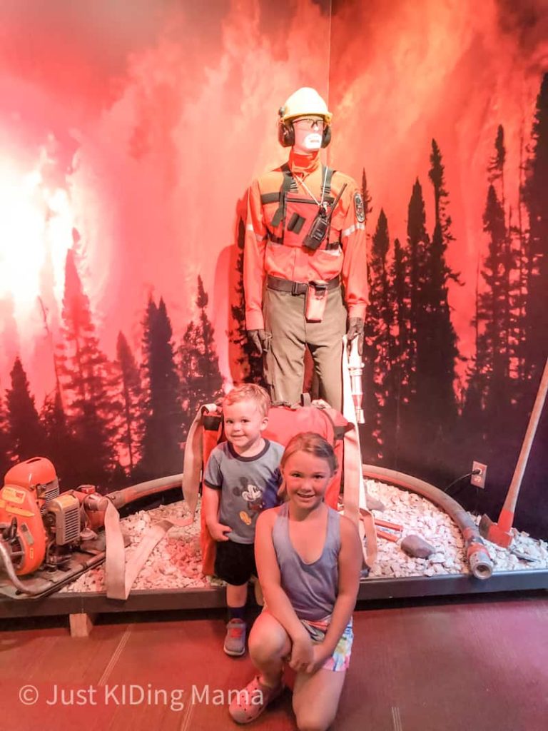 Mannequin dressed in wild fire fighting gear. Little boy and girl pose in front. 