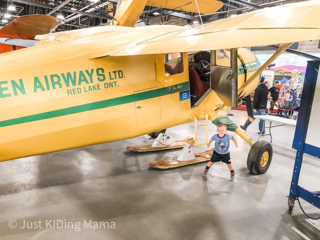 Little Boy stands under Yellow bushplane