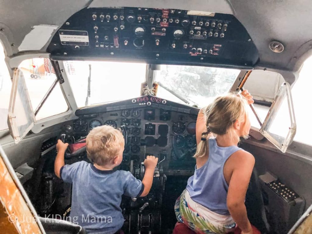 little boy and girl inside of the cockpit of a plane playing with the flight instruments. 