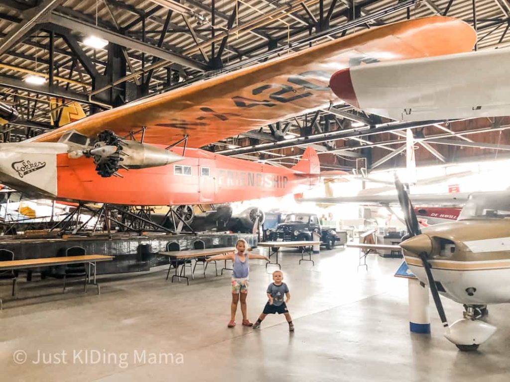 Boy and Girl standing under a large orange plane