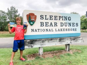 Boy standing in front of Sleeping Bead Dunes National Lakeshore sign