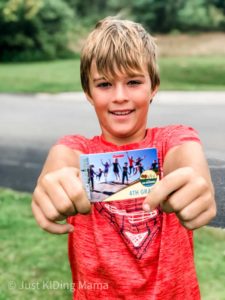 Boy in read shirt holding out a 4th Grade National Park Pass