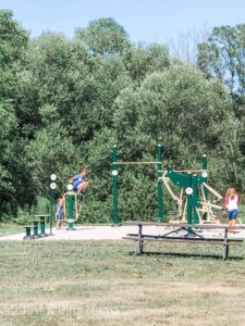 2 boys and a girl playing on an adult exercise playground. Equipment is green and yellow and would be used for strength training