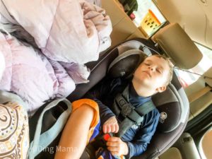 Boy in Baiting suit and navy blue sun shirt, asleep in his carseat.