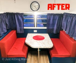 Vintage Camper Dinette with blue curtains and benches and red cushions with white table. 