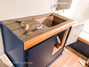 Blue lower cabinets, white wall, and wood grain plank flooring as counter top 