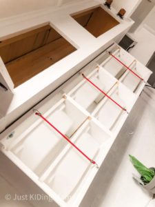 White IKEA bin cabinet with 6 white drawers, hooked together with red bungee cords