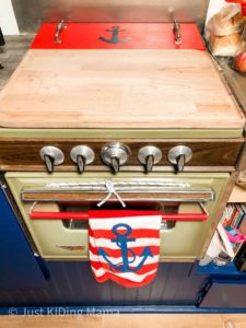 Green Vintage Stove with red white and blue towel hanging from a bar on the front of it. 