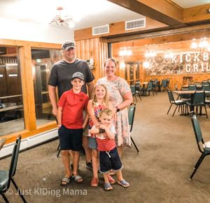 Family of mom, dad, 2 boys and a girl are standing inside of a restaurant 