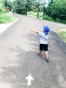boy walking down a sidewalk with one way direction arrows