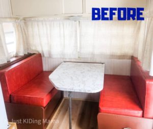 Camper Dinette with red vinyl cushions and white curtains